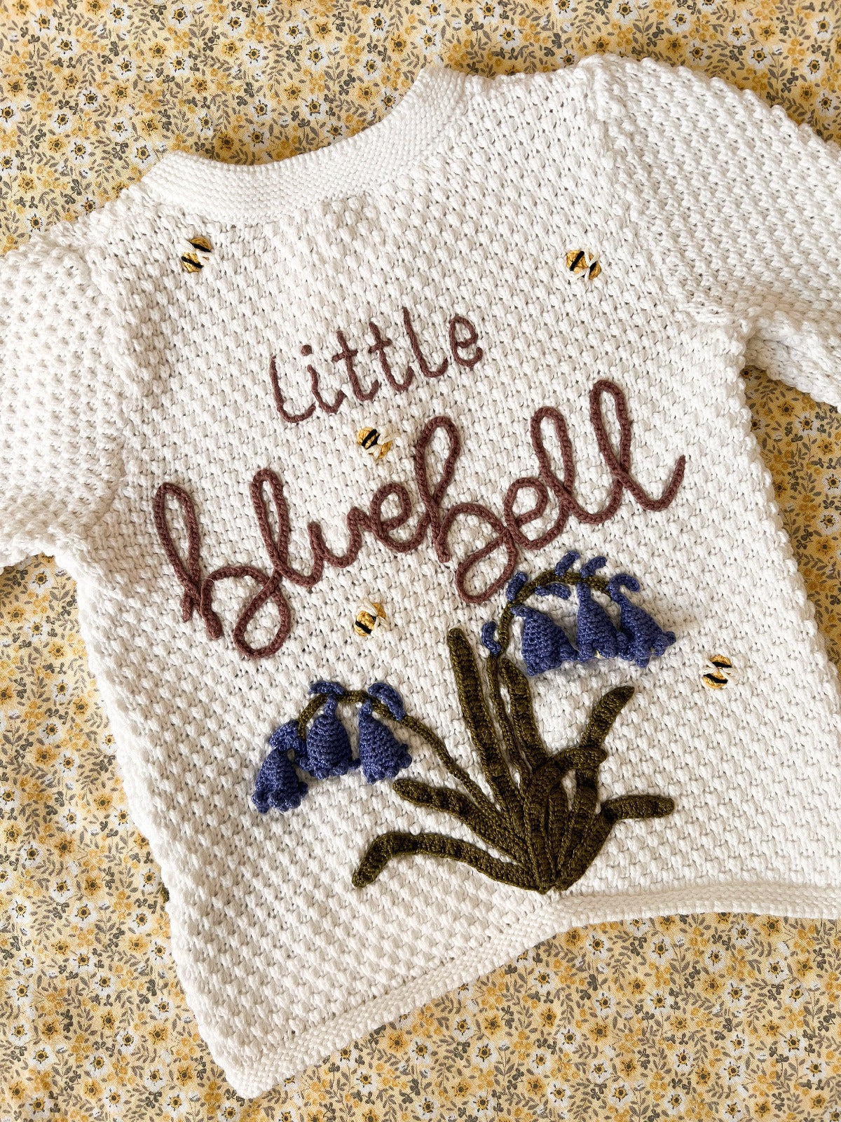 A white handknitted jumper with the words little bluebell