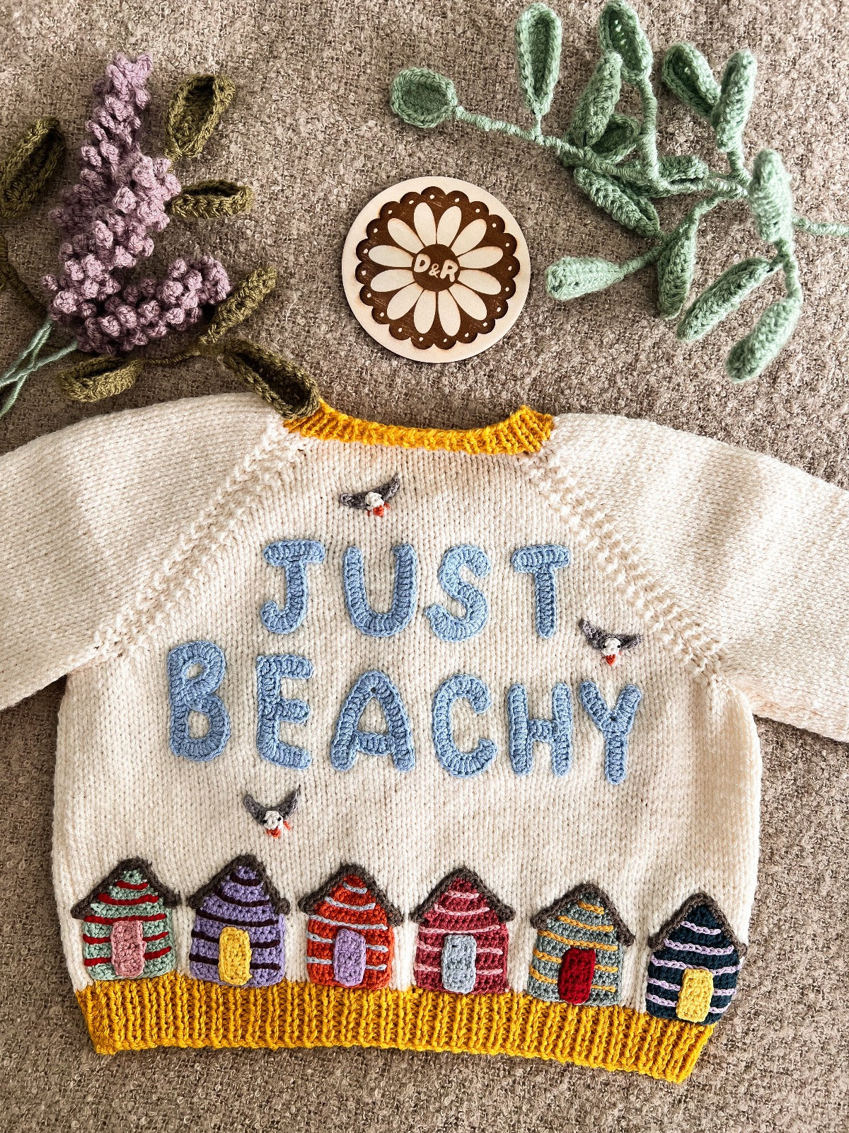 Handknitted cardigan with beach huts and the words just beachy