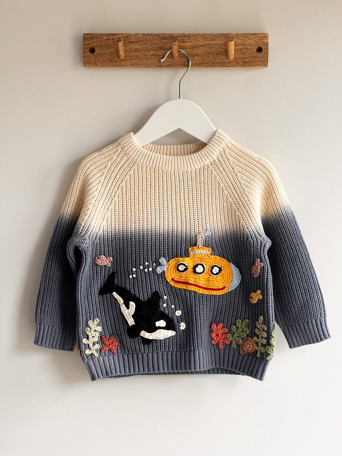 A children's jumper with a yellow submarine and killer whale crocheted on the front